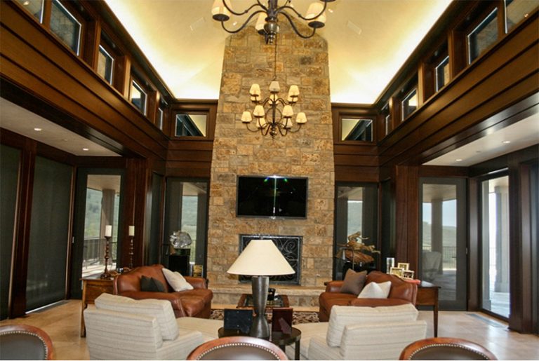Great room with paneled walls and a stone fireplace surround